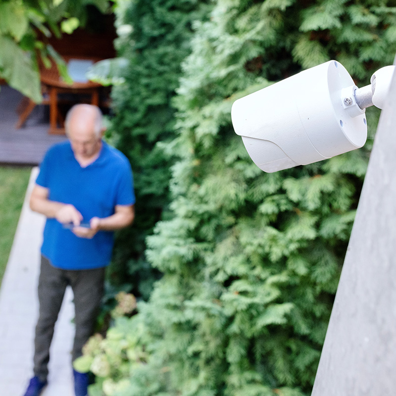 Senior man installing security camera for home surveillance