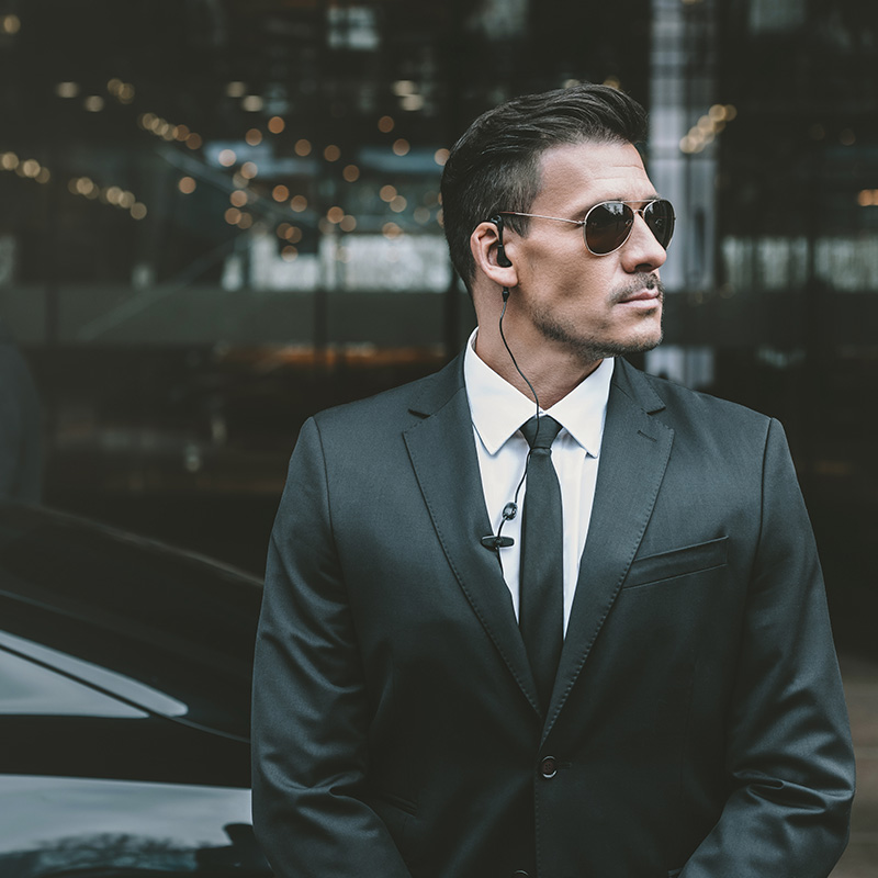 Bodyguard standing at businessman car and reviewing territory